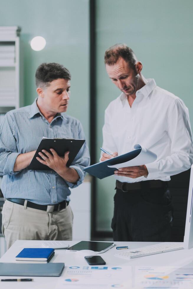 Two businessmen working together Analyze financial reports with charts and graphs while using the calculator to calculate budget, income, taxes, business growth. Startup business idea. photo