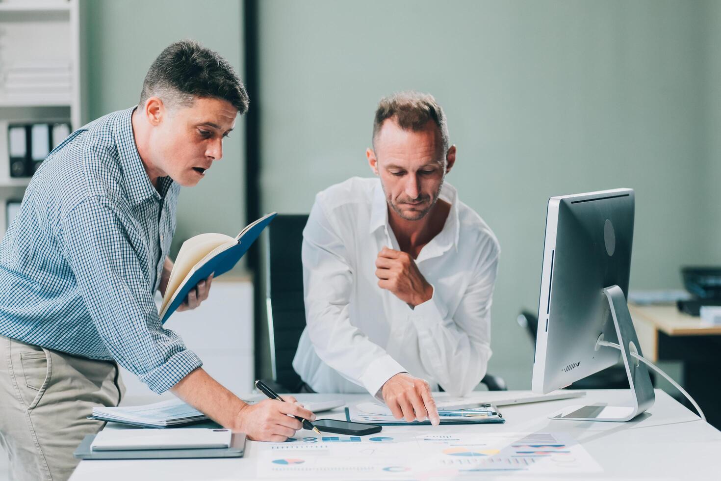 Two businessmen working together Analyze financial reports with charts and graphs while using the calculator to calculate budget, income, taxes, business growth. Startup business idea. photo
