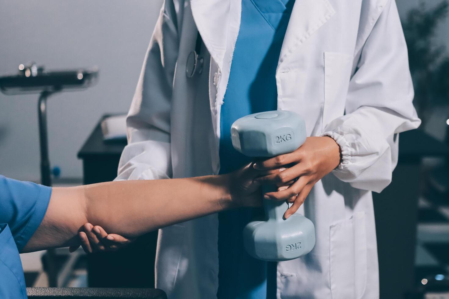 Old woman training with physiotherapist using dumbbells at home. Therapist assisting senior woman with exercises in nursing home. Elderly patient using dumbbells with outstretched arms. photo