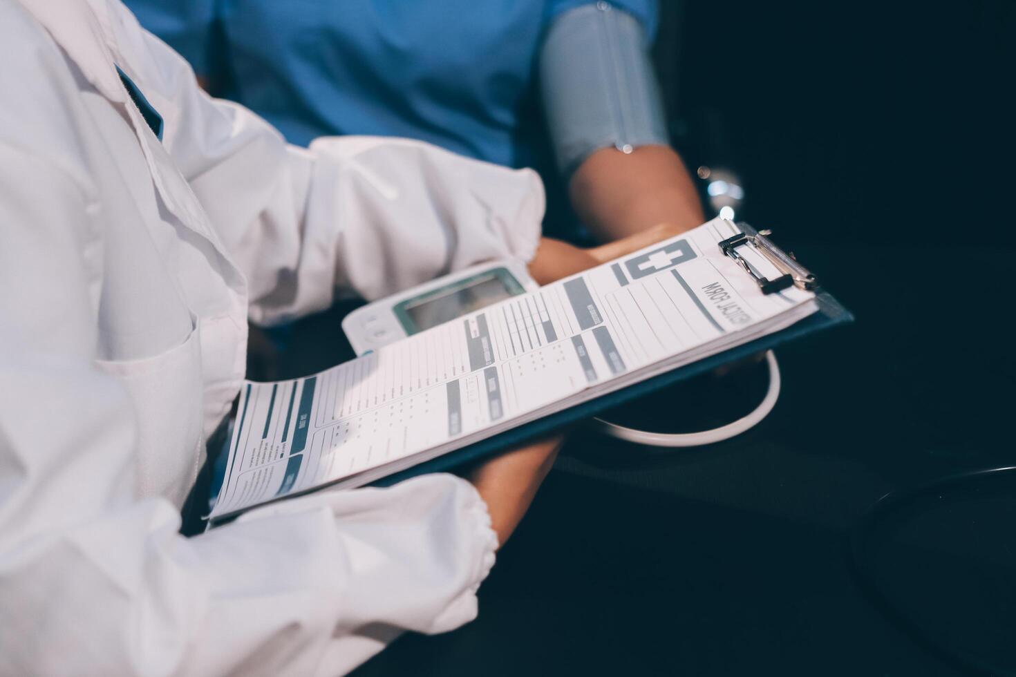 A doctor taking a patient's blood pressure. The patient's arm is equipped with a blood pressure cuff, and the doctor is using a blood pressure monitor. photo