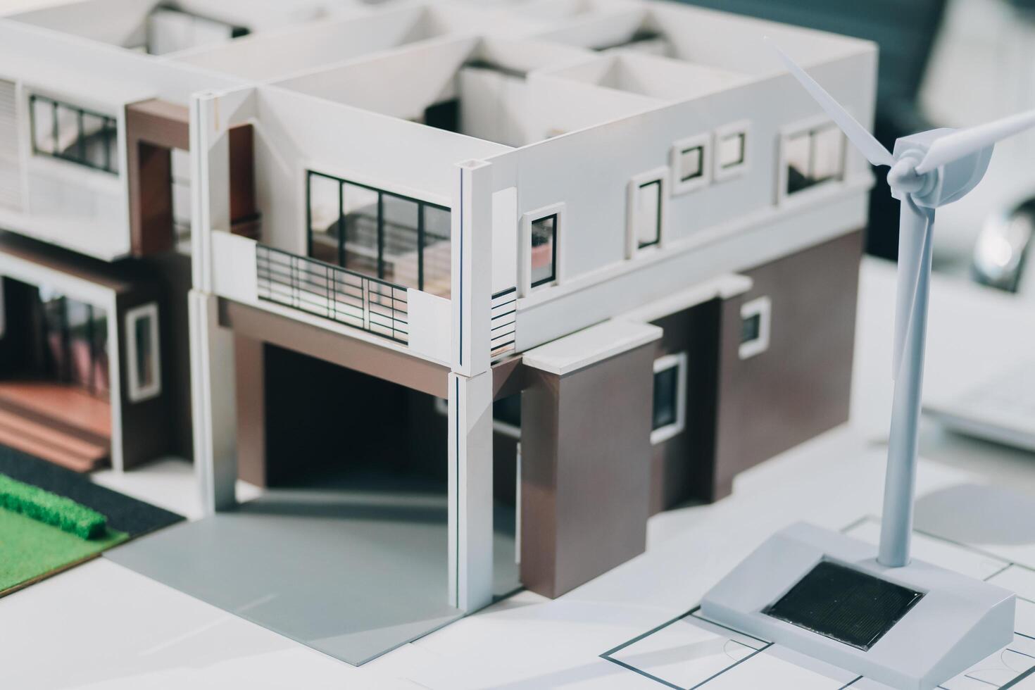 Engineers meeting about wind turbine model and house model. Renewable energy and housing development concept. Team of architects and engineers in modern office discussing design structure. photo