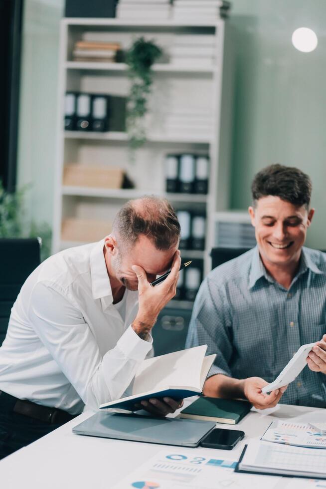 Two businessmen working together Analyze financial reports with charts and graphs while using the calculator to calculate budget, income, taxes, business growth. Startup business idea. photo