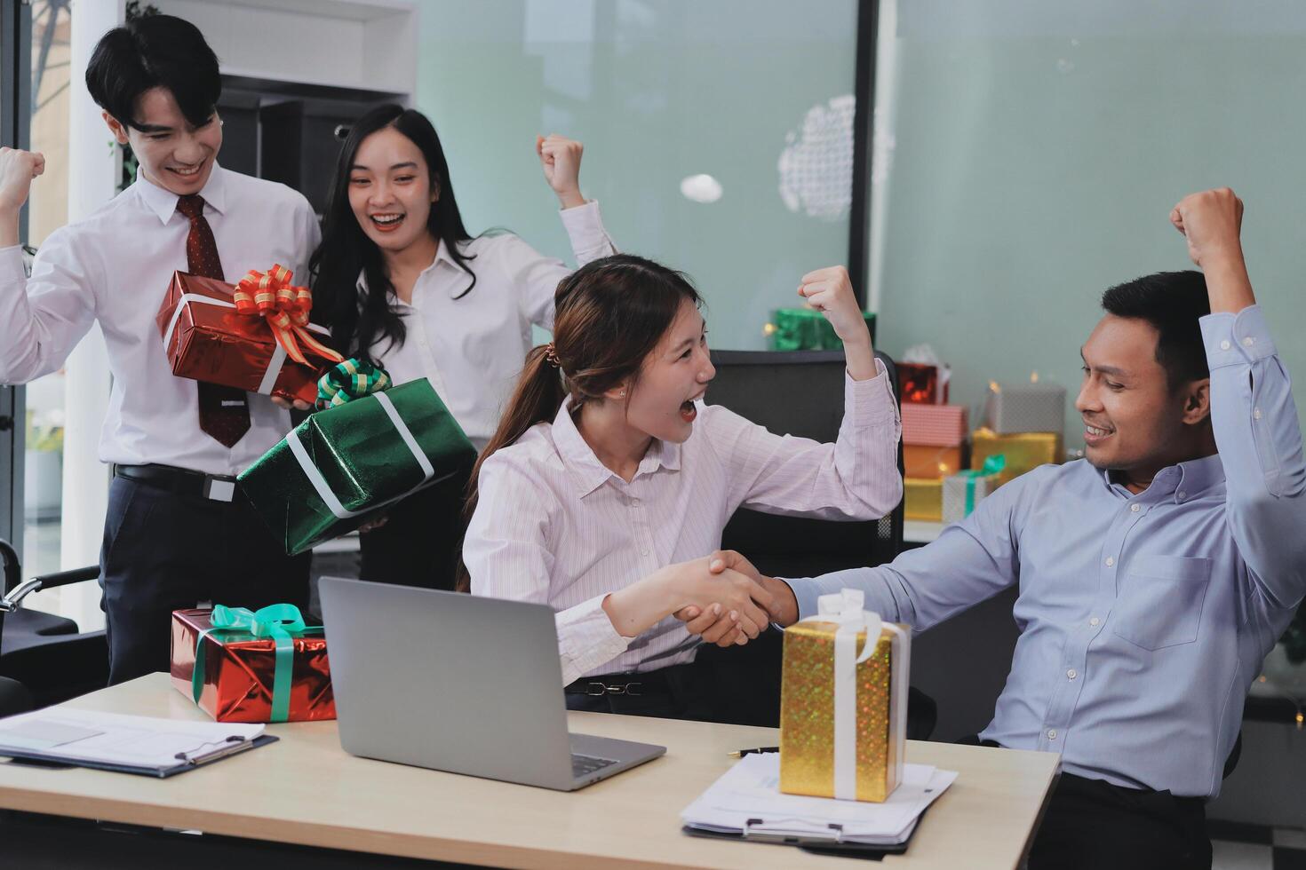 full length view of a group of business team wearing red Santa hat and exchange gift box together in the office for Christmas. photo