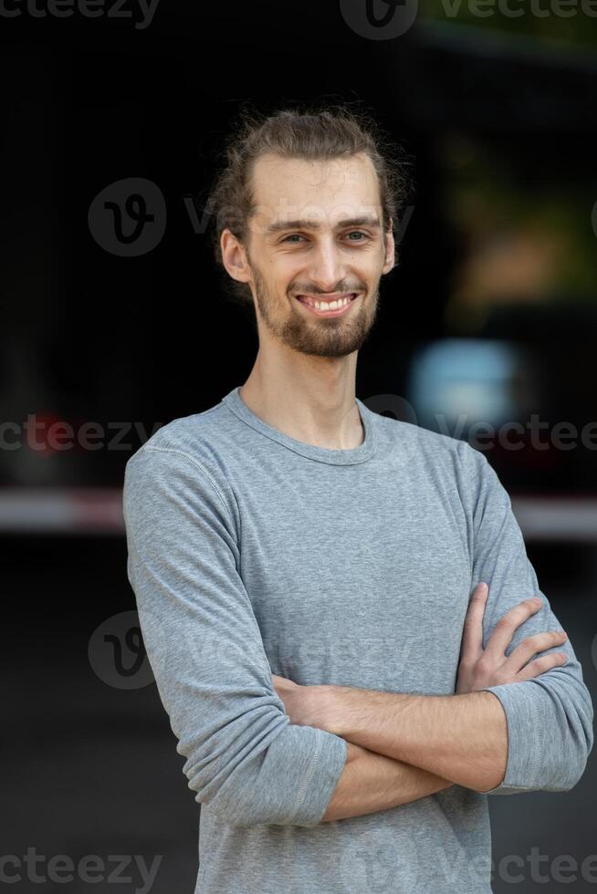 Portrait of a young successful businessman with crossed arms in front of the company photo