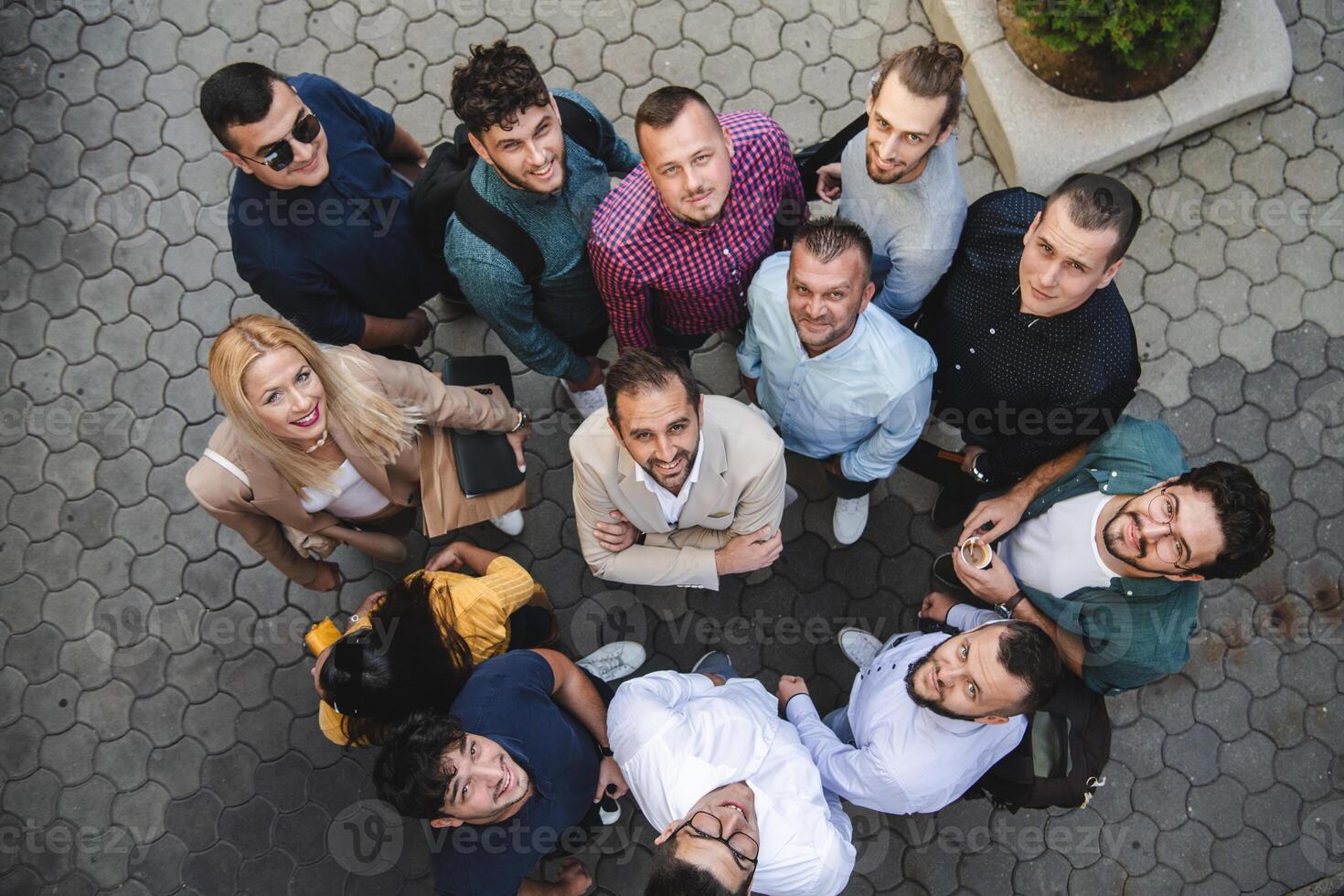 Top view photo of a group of business people and colleagues standing together holding hands, looking towards the camera, symbolizing unity and teamwork.