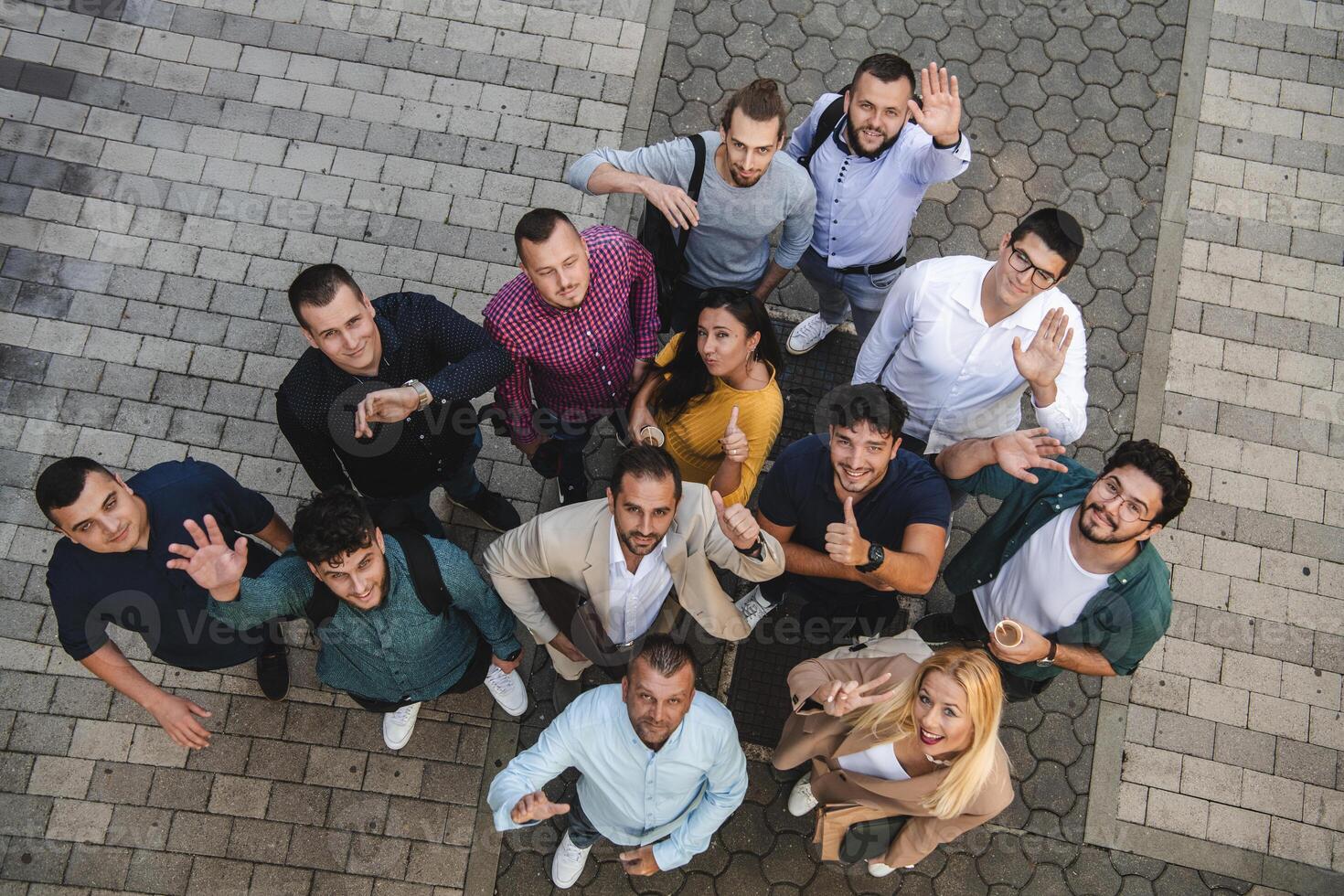 Top view photo of a group of business people and colleagues standing together holding hands, looking towards the camera, symbolizing unity and teamwork.