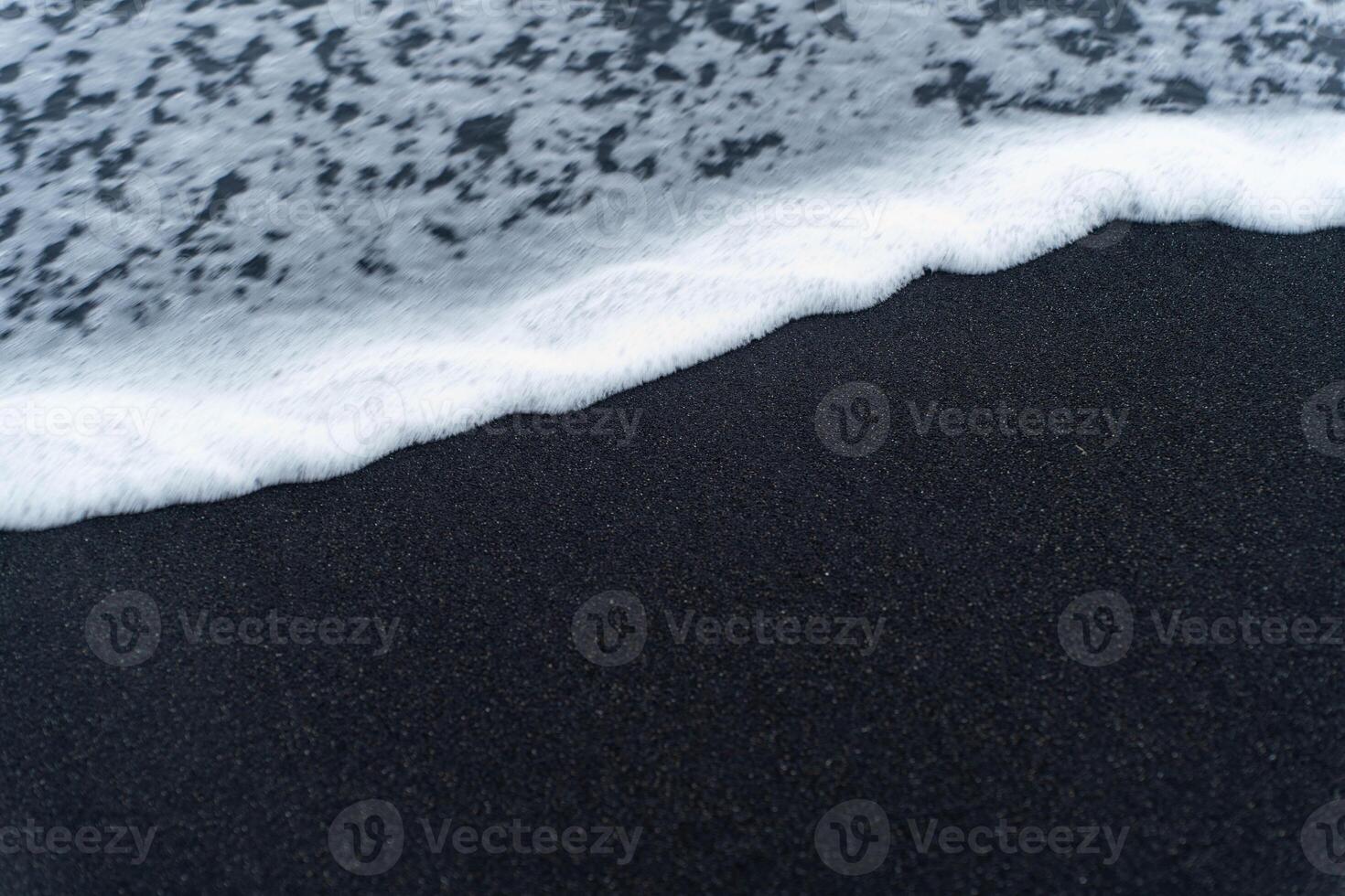 Sea foam on a black beach photo