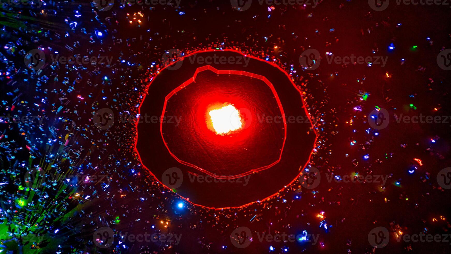 Crowd Surrounding Red Light Emitting From Circular Structure photo