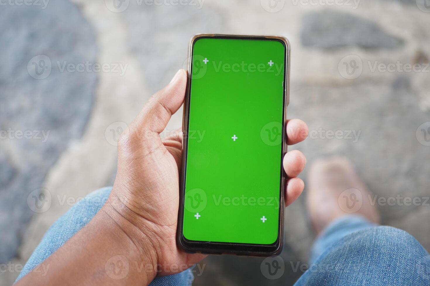 A Hand Holding a Smartphone Featuring a Green Screen Ideal for Editing and Mockup Purposes photo