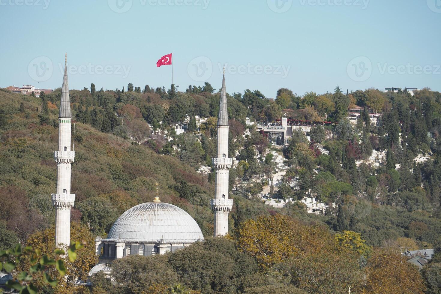A stunning mosque with elegant minarets and a Turkish flag, set in a scenic landscape photo