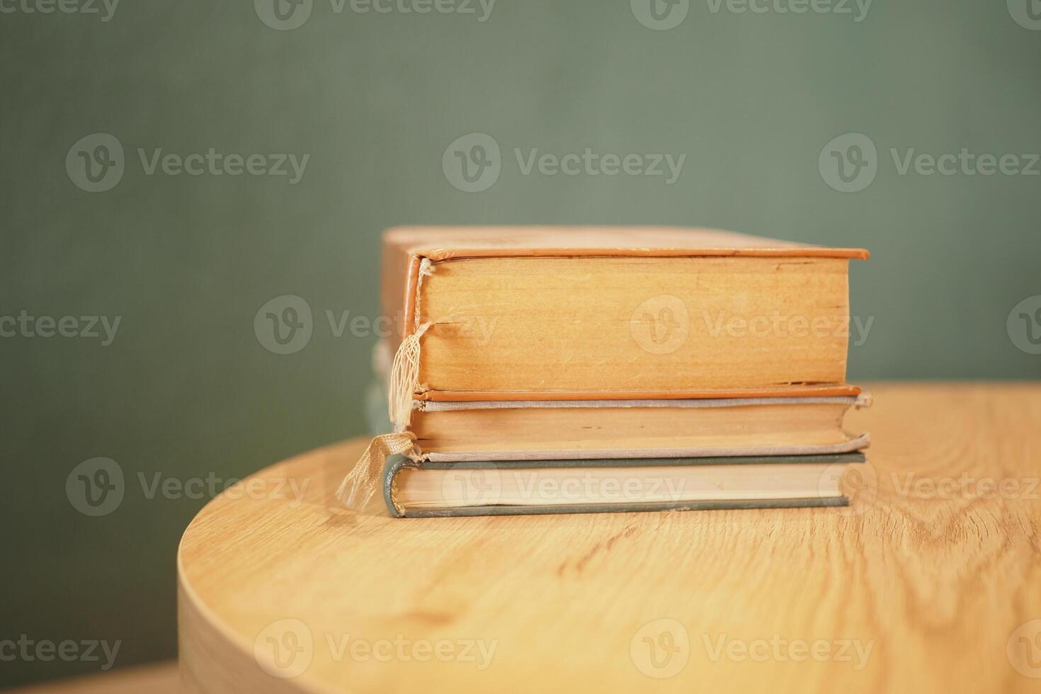 A Beautiful Arrangement of Stacked Books on a Wooden Table Set Against a Subtle Green Background photo
