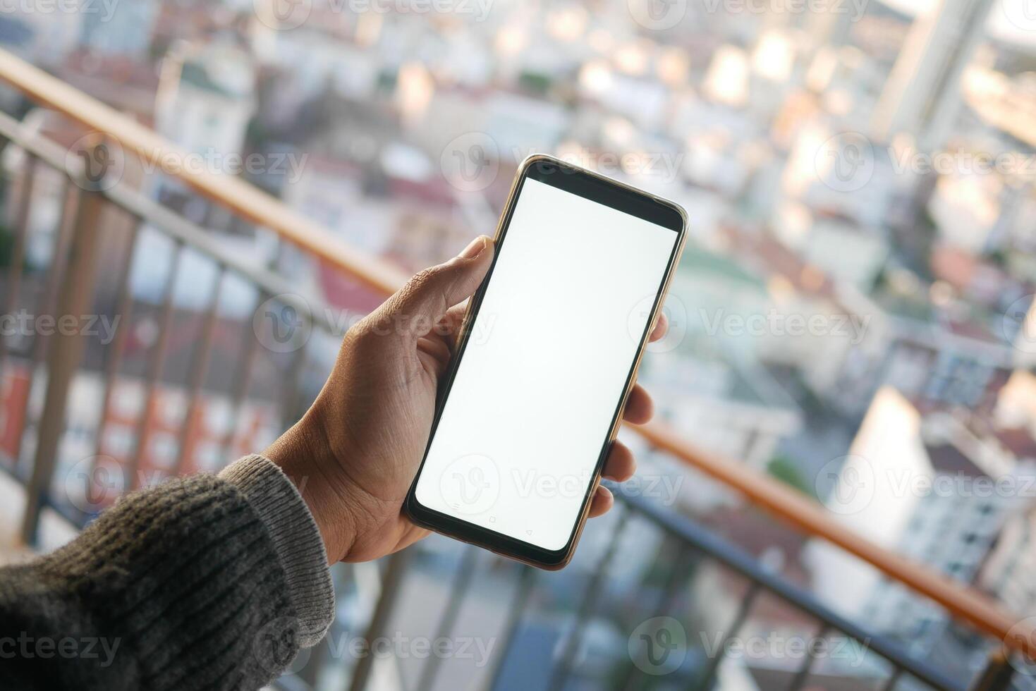 A hand is holding a smartphone against the backdrop of a bustling city in the background photo