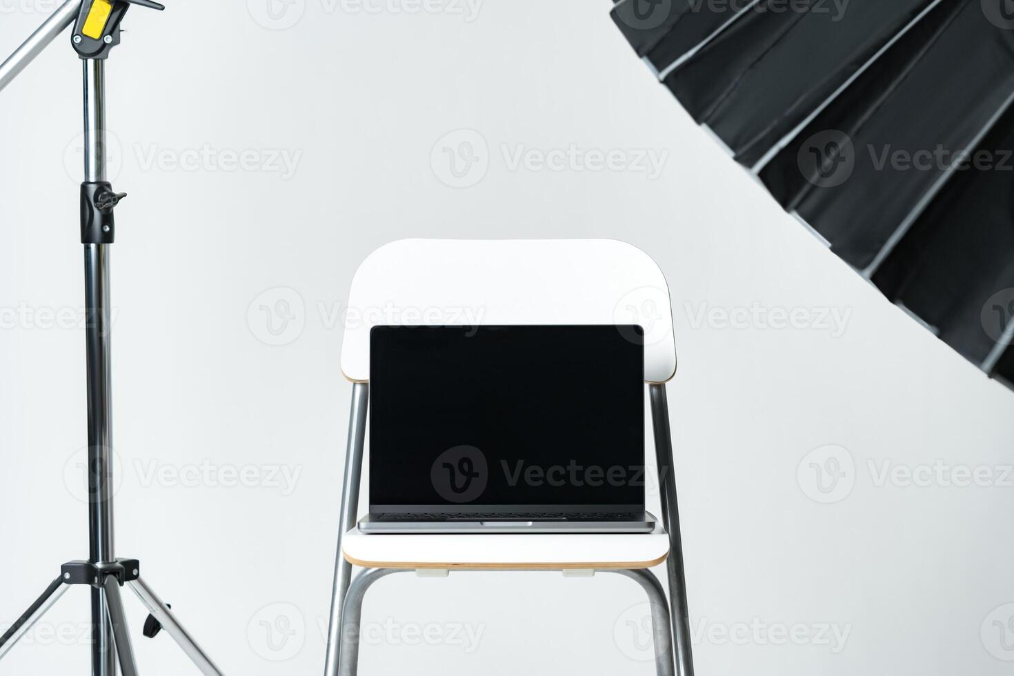 Laptop with black screen and photography equipment in photostudio photo