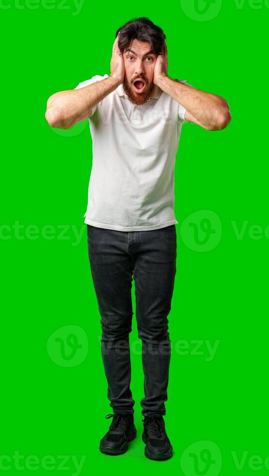 A man with a surprised expression holds his face while against a vibrant green background photo