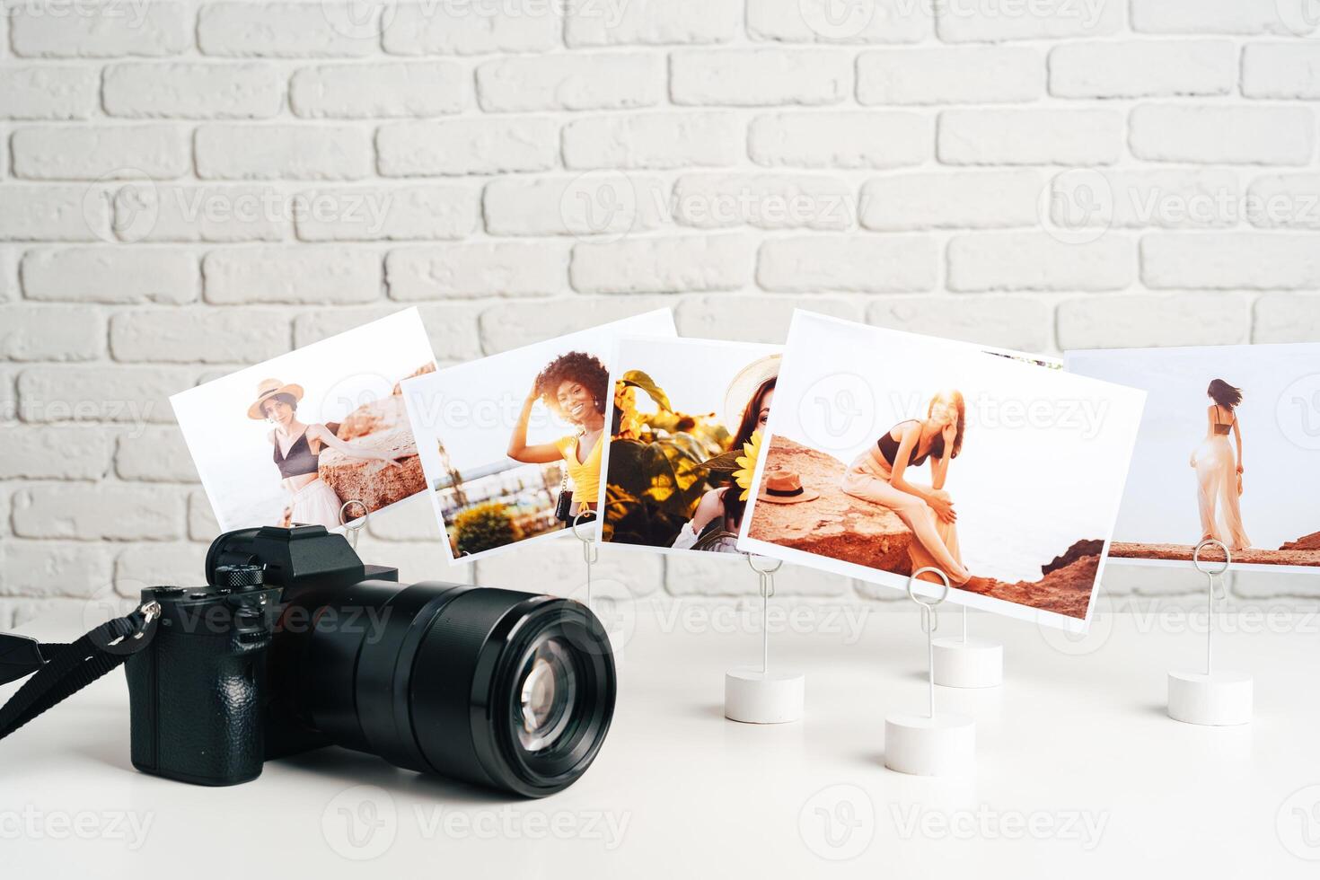 Camera and colorful printed photos of women on desk close up