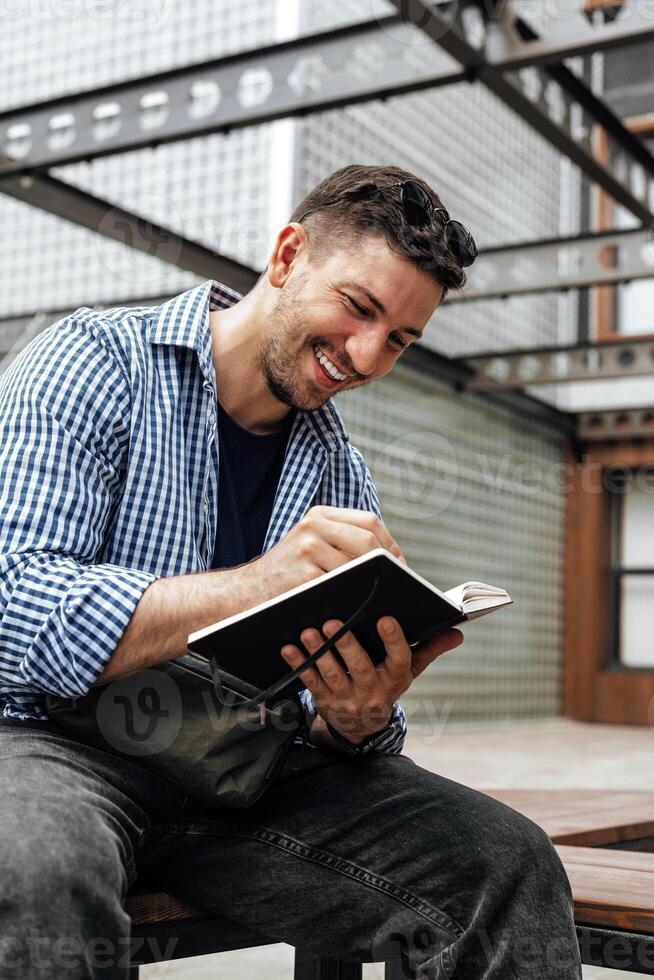 A person writes in a notebook while sitting on a park bench photo