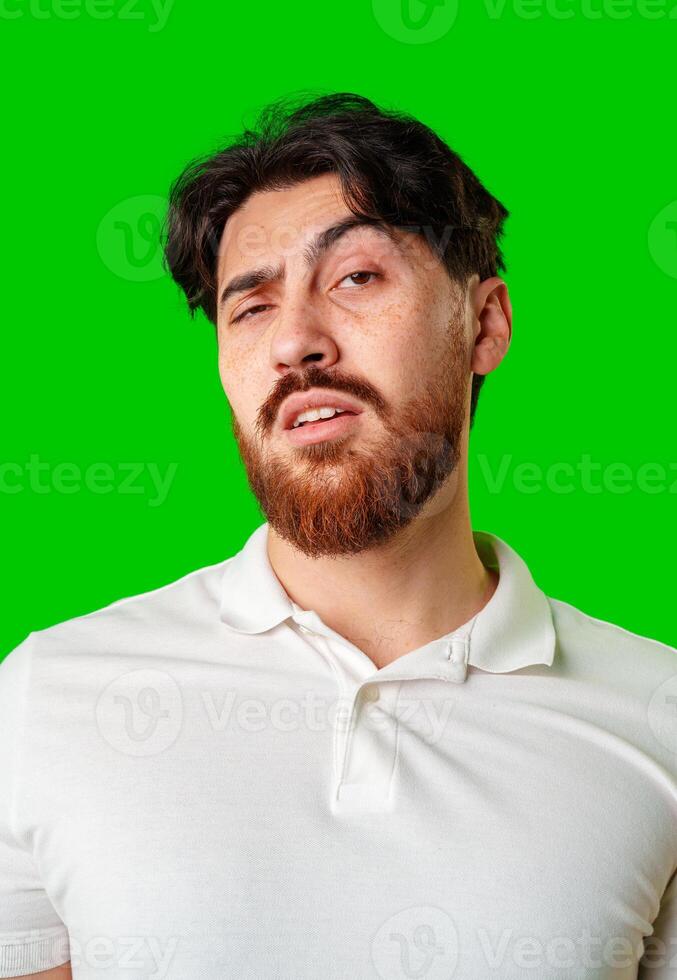 A young man with a beard showing a serious expression against a vibrant green background photo