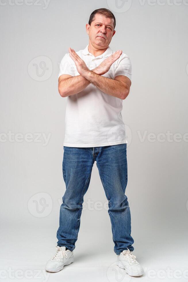 A man making a gesture of refusal with arms crossed against a light background photo