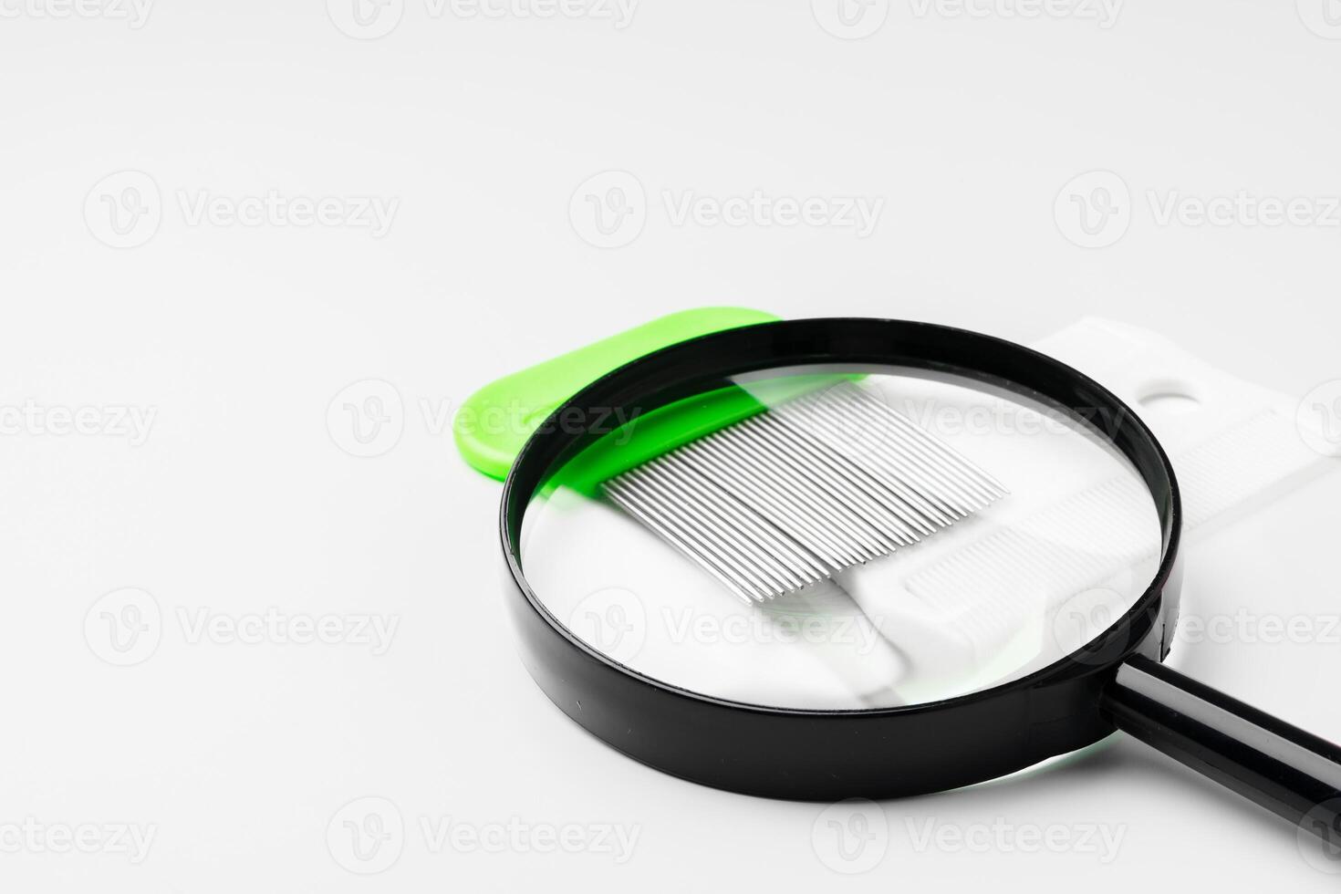A magnifying glass and lice comb placed side by side on a clean white background photo