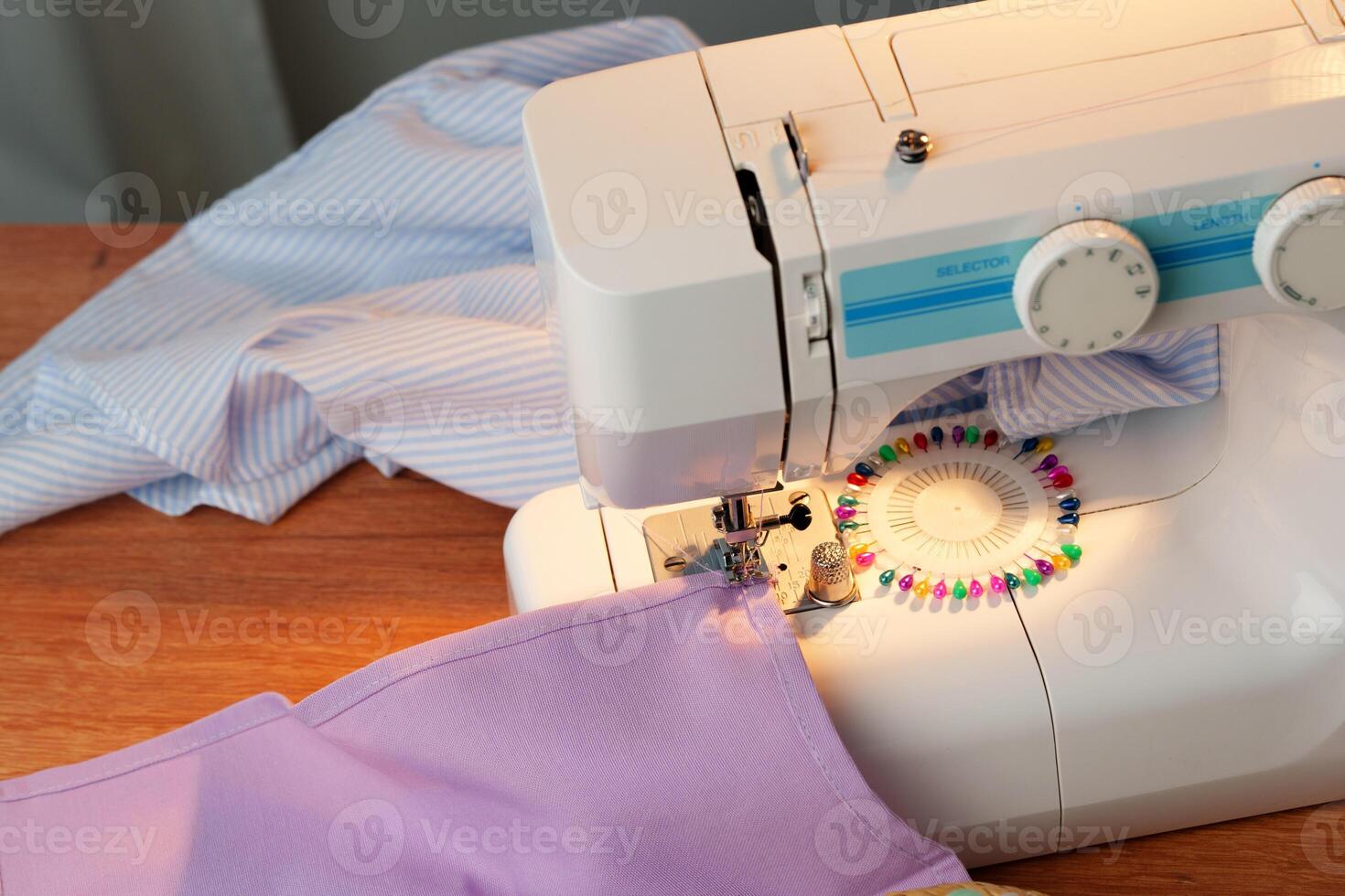 Sewing machine in use on a wooden table, stitching a light fabric in a well-lit indoor workspace photo