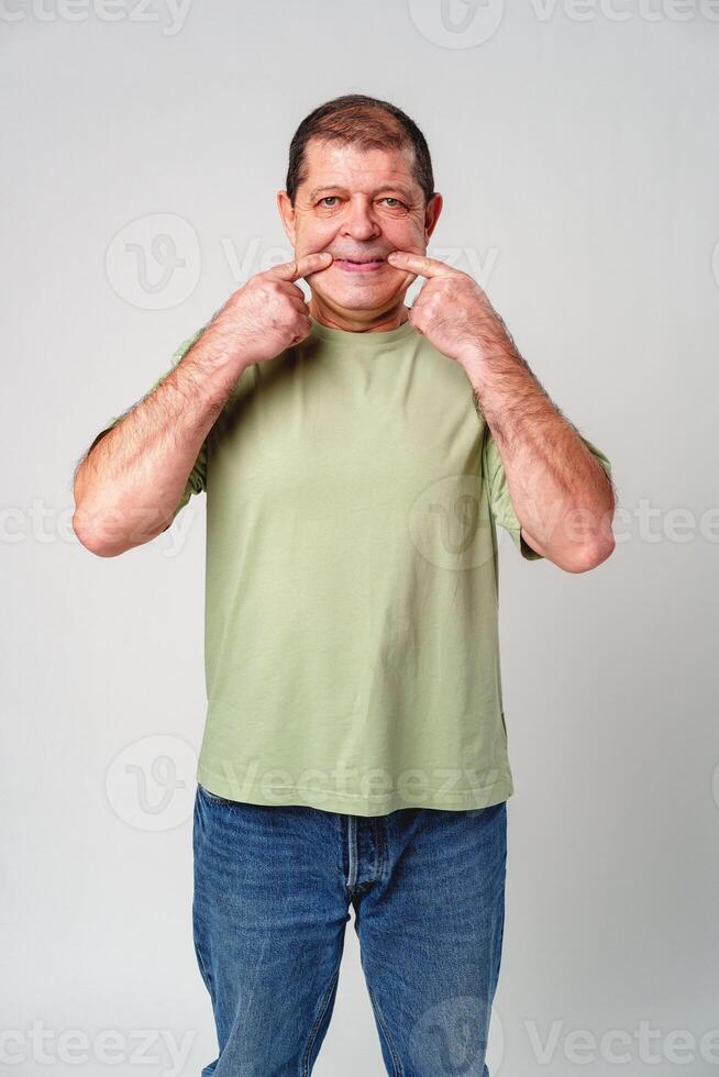 An older man smiling while making a funny face in a neutral studio background photo