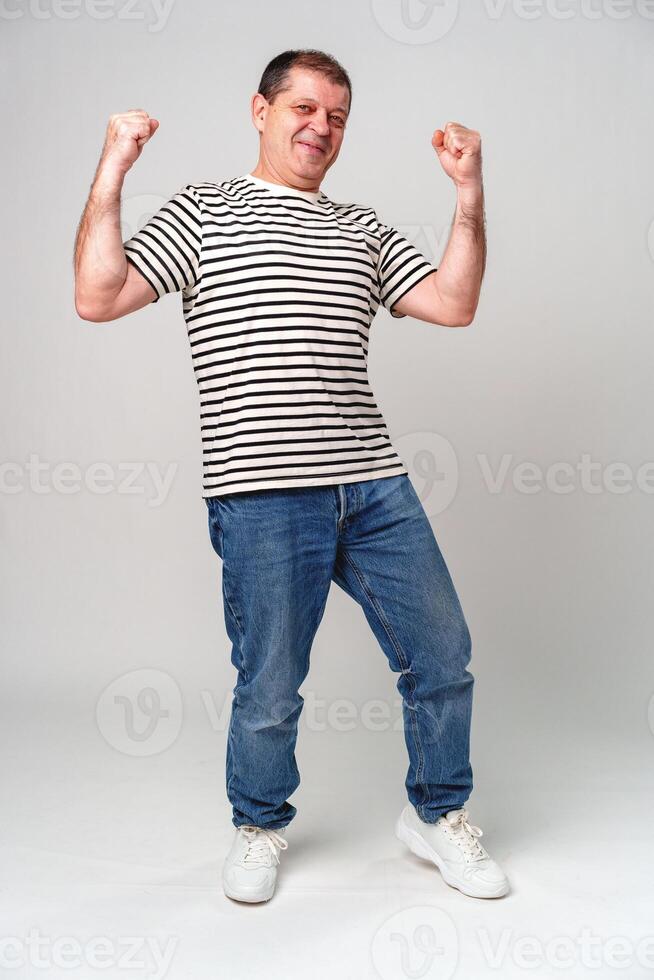 A cheerful man in a striped shirt strikes a playful pose against a light background, showcasing joy and confidence photo