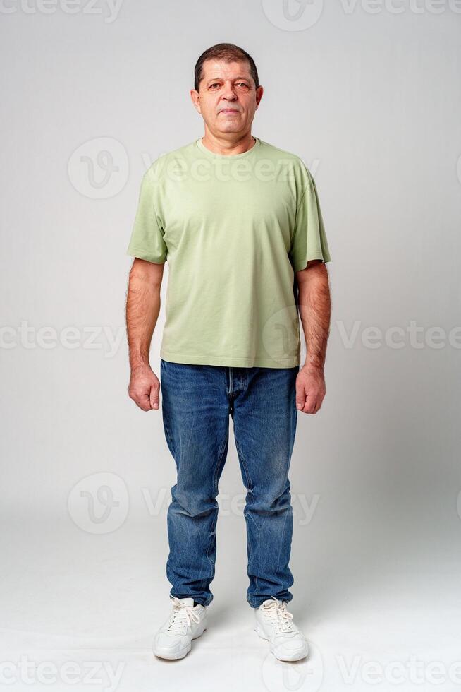 A man standing confidently in casual attire against a neutral background, showcasing a relaxed pose photo