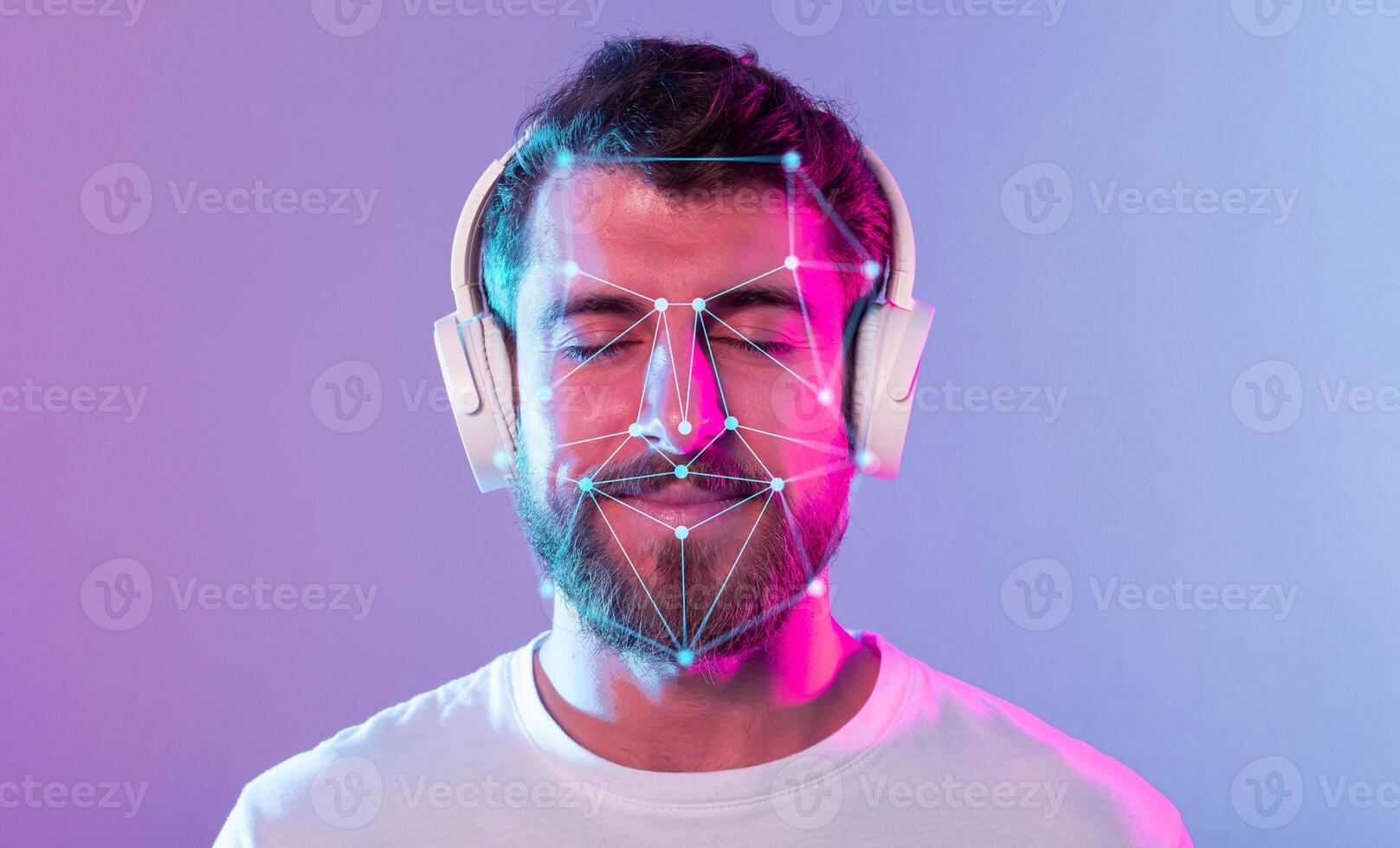 A young man with a beard listens to music while wearing headphones, enjoying a moment of relaxation. Colorful lights enhance the ambiance around him, showcasing facial recognition patterns. photo