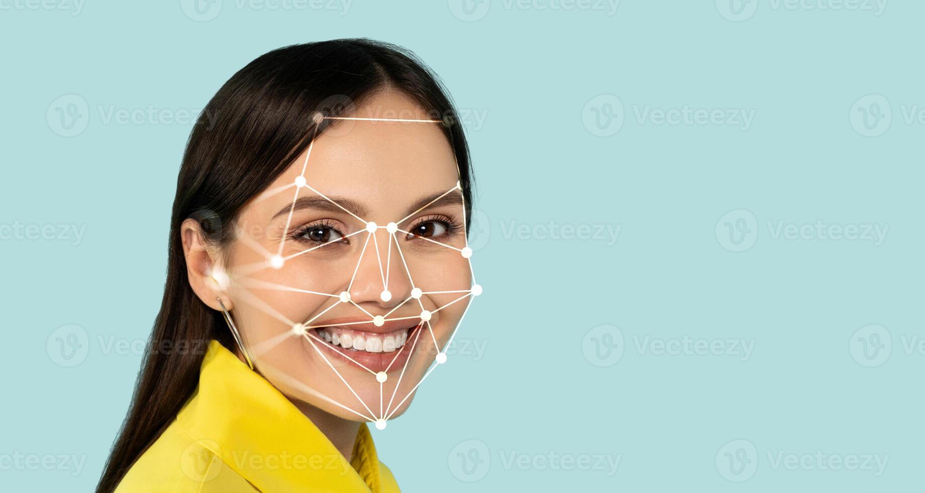 A woman is smiling brightly while a digital facial recognition grid is superimposed on her face. The background is a soothing light blue, emphasizing her cheerful expression. photo