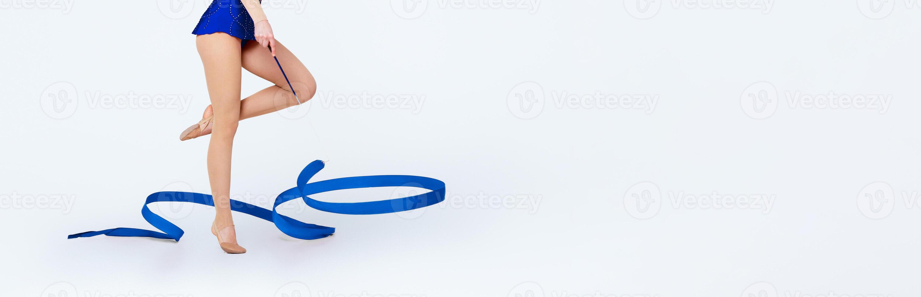 Unrecognizable female gymnast with red ribbon on white studio background, close up of legs. Panorama photo