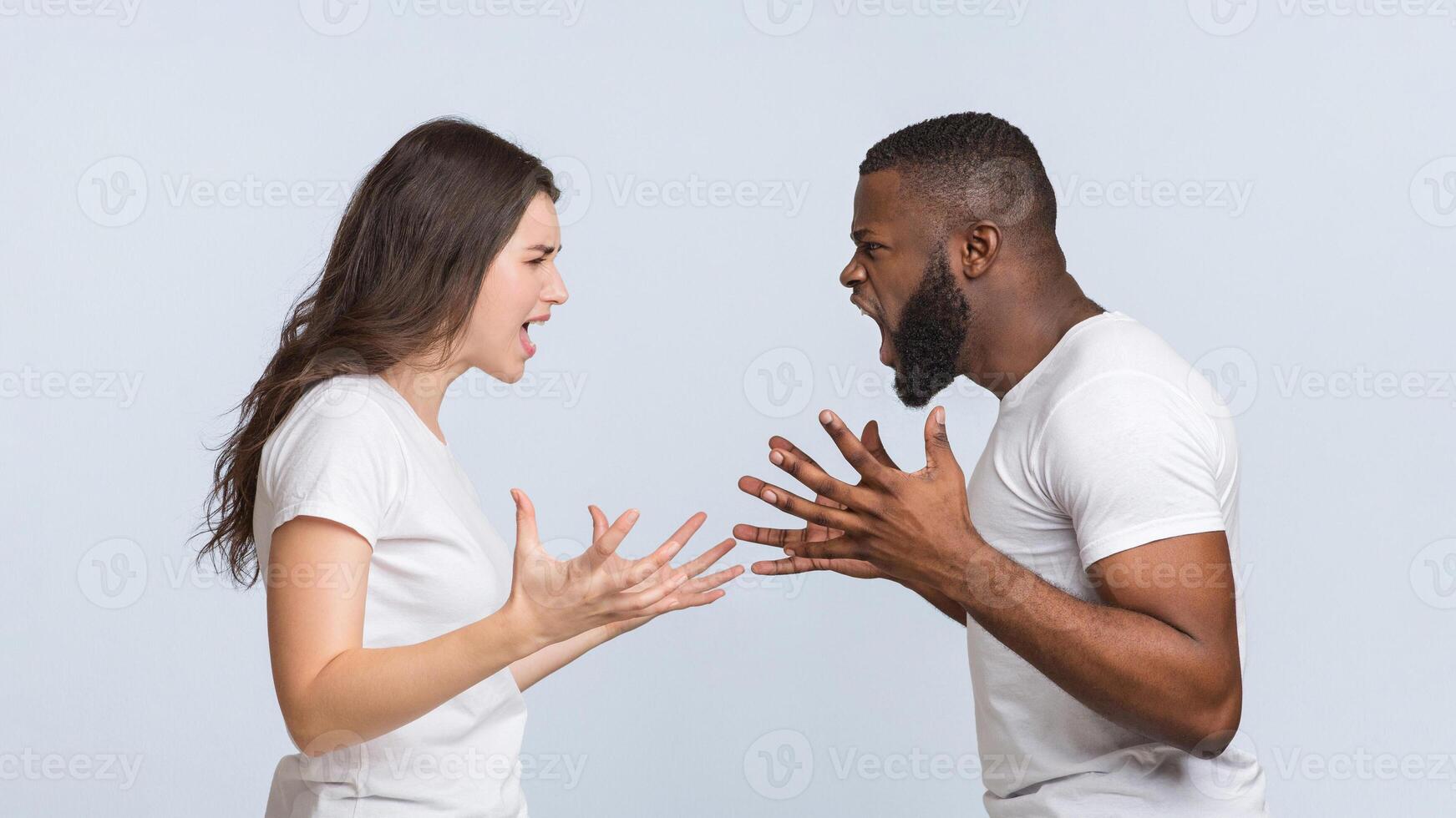 Relationship crisis. Furious multiracial couple yelling at each other, emotionally arguing and gesturing over light studio background, panorama photo