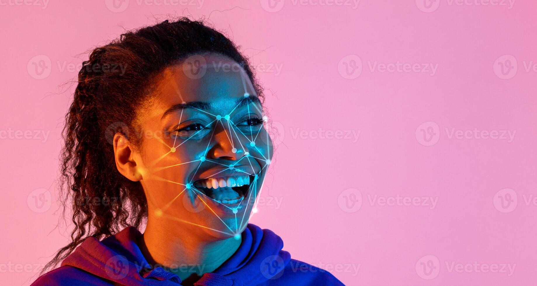 Black woman is smiling joyfully while vibrant lights illuminate her face, showcasing facial recognition patterns. The colorful background enhances the enthusiastic atmosphere of the moment. photo