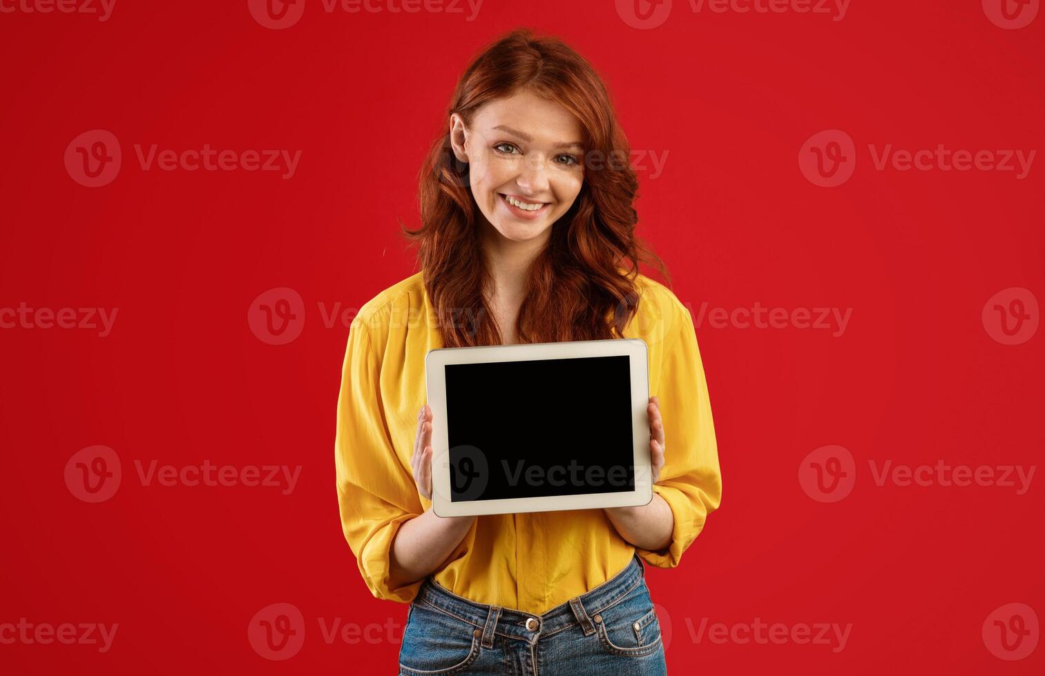 Red-Haired Student Girl Showing Tablet Computer Blank Screen Posing On Green Studio Background. Great Application. Mockup photo