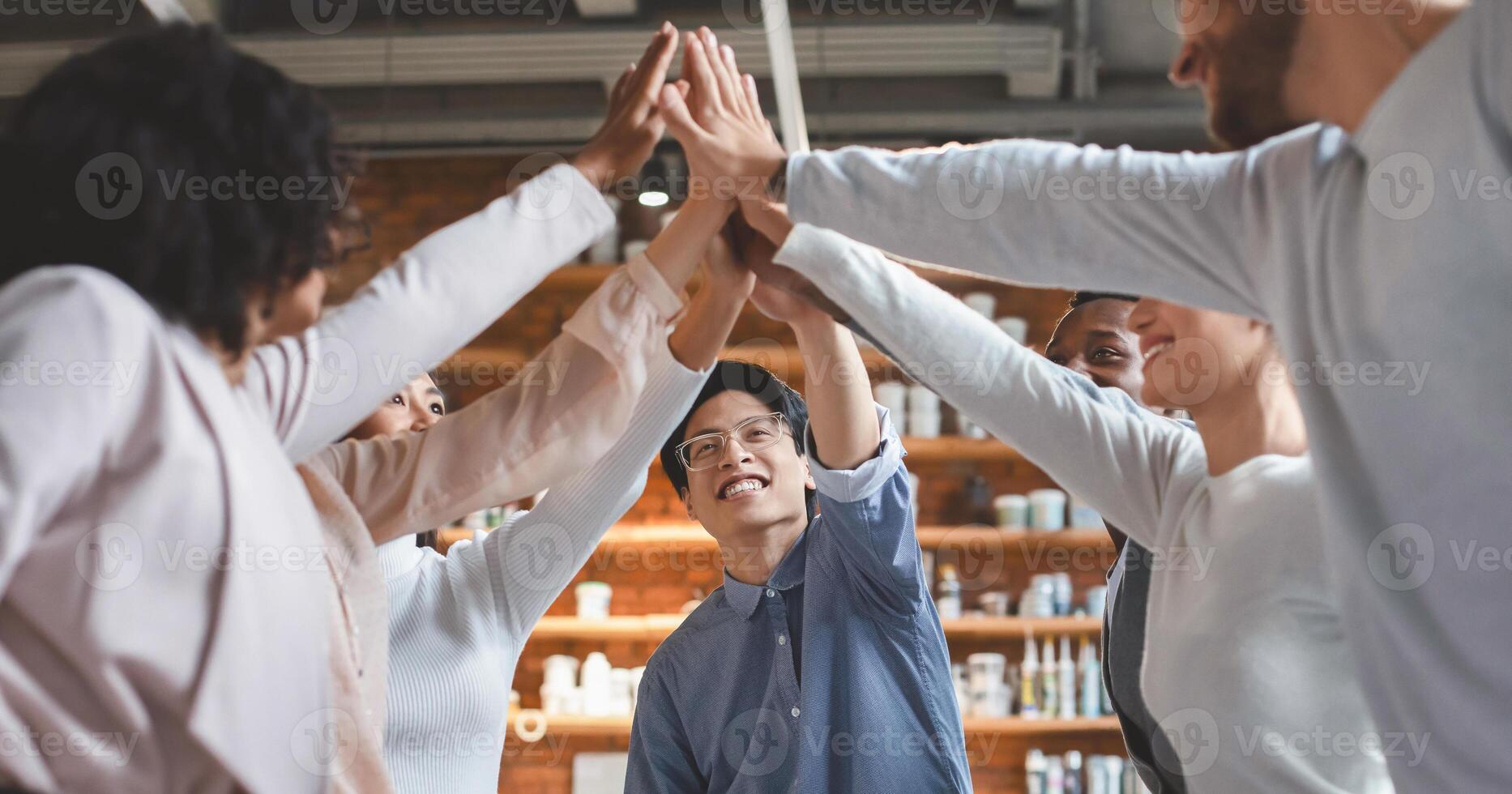 Multiracial young team giving high five, enjoying successful business meeting, teamwork concept photo