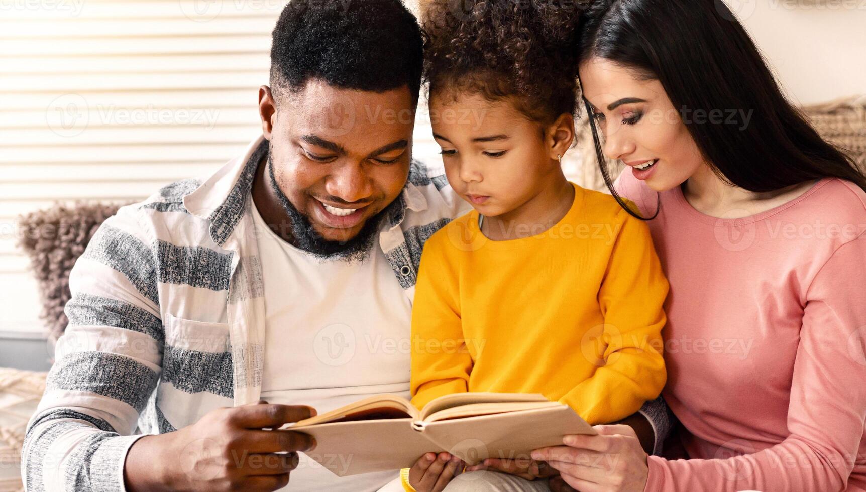 Happy international family reading book together at home during covid-19 quarantine photo