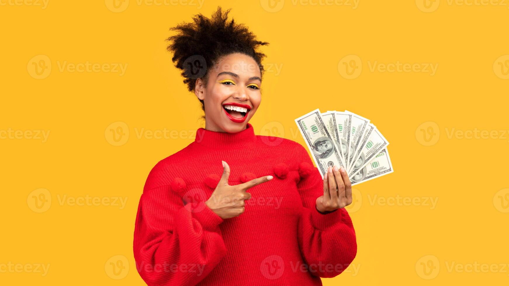 Your Prize. Excited afro woman holding bunch of money, pointing at cash, isolated over orange wall, copyspace photo