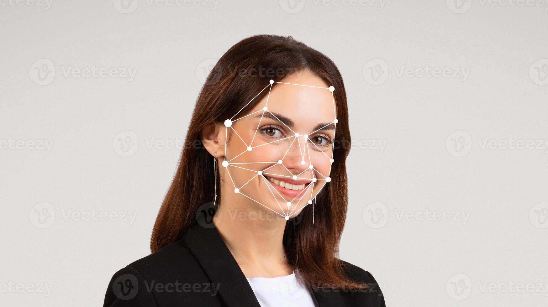 The woman stands confidently in a business suit, smiling towards the camera. Digital facial recognition points are overlaid on her face, highlighting technology's role in identity verification. photo