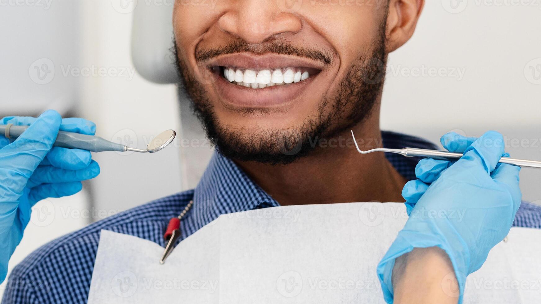 Close up of dentist hands in protective gloves with tools and smiling patient black man, panorama photo