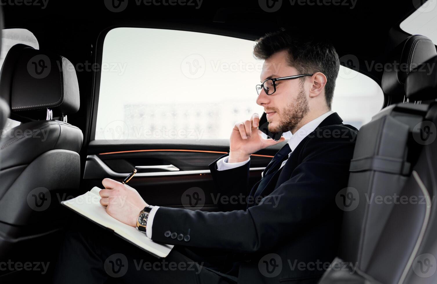Important Call. Side view of focused businessman planning his day and talking on cell phone, going to office by car photo