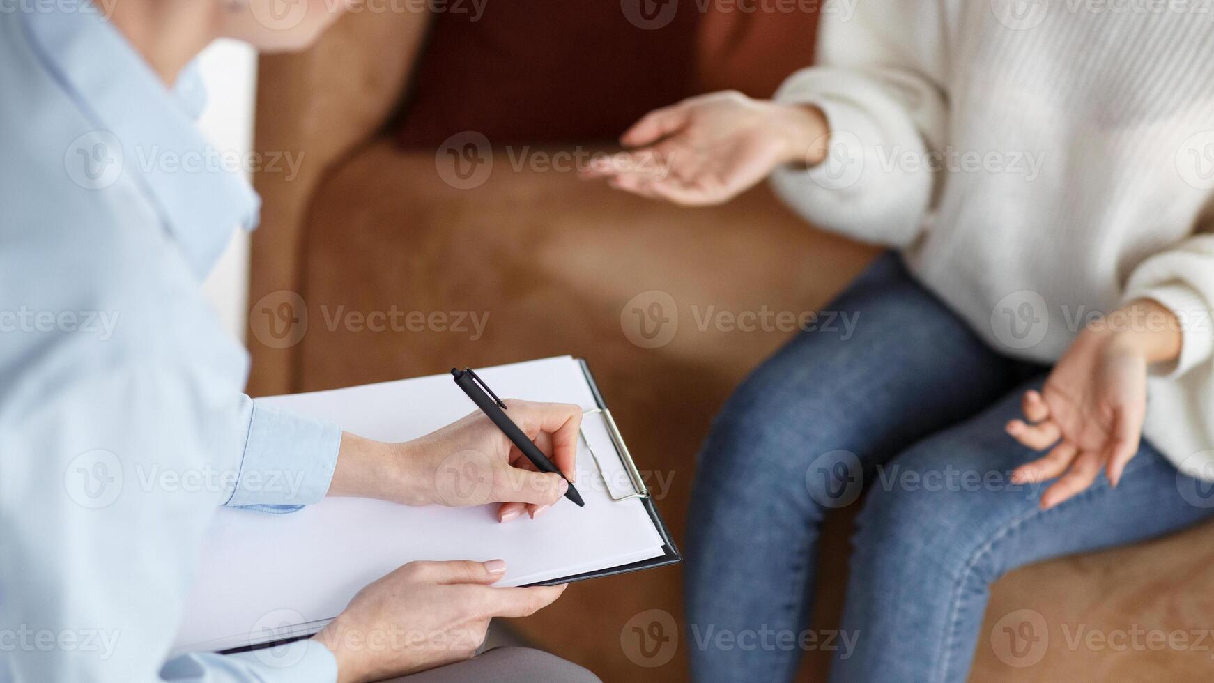 Psychologist Talking With Female Patient Taking Notes During Appointment Sitting In Office. Selective Focus, Cropped photo