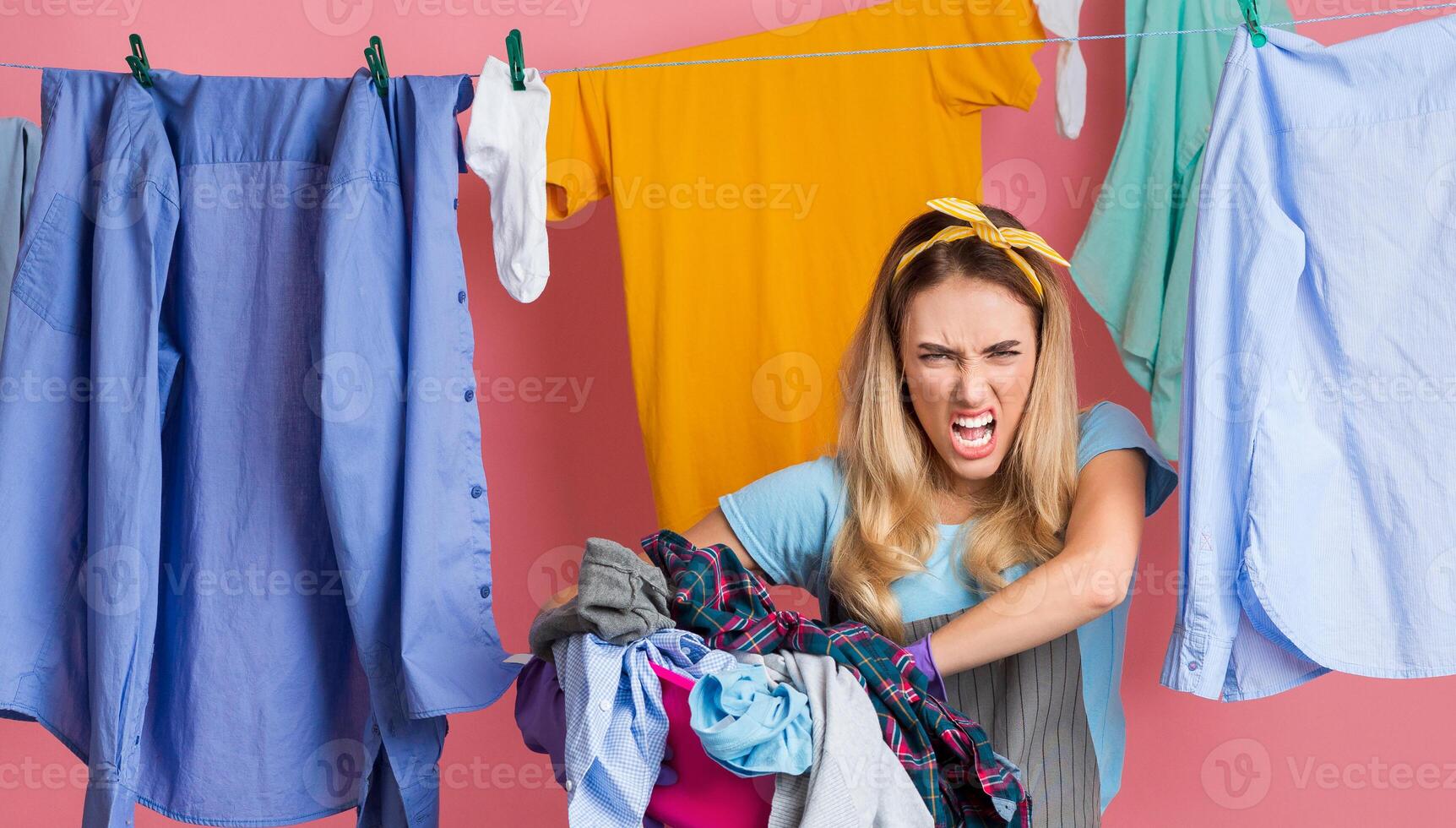 Wicked housewife with dirty laundry, powder and conditioner on pink background photo