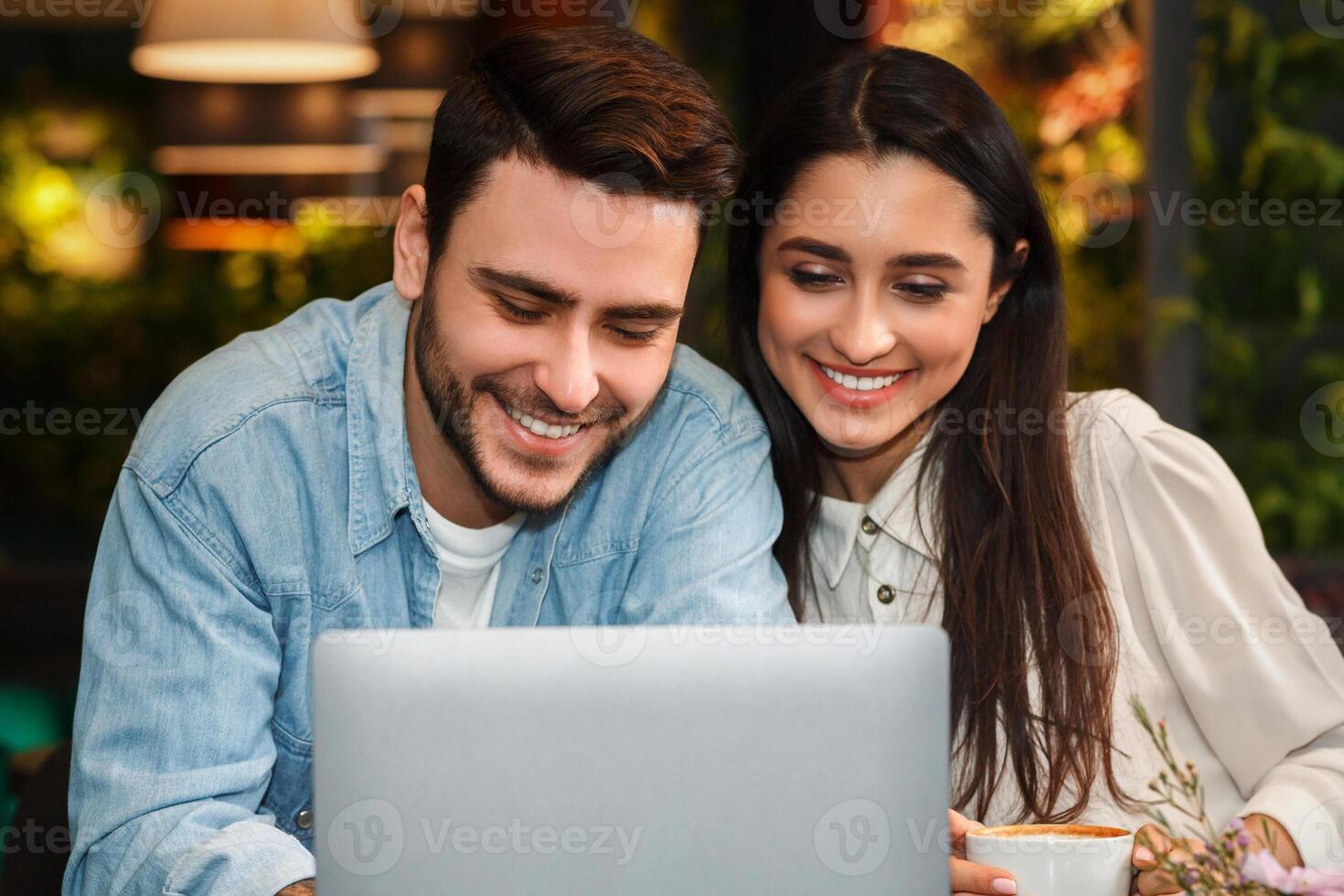 Happy Couple Using Laptop Browsing Internet Having Date Enjoying Coffee Sitting In Cozy Cafe. Modern Relationship photo