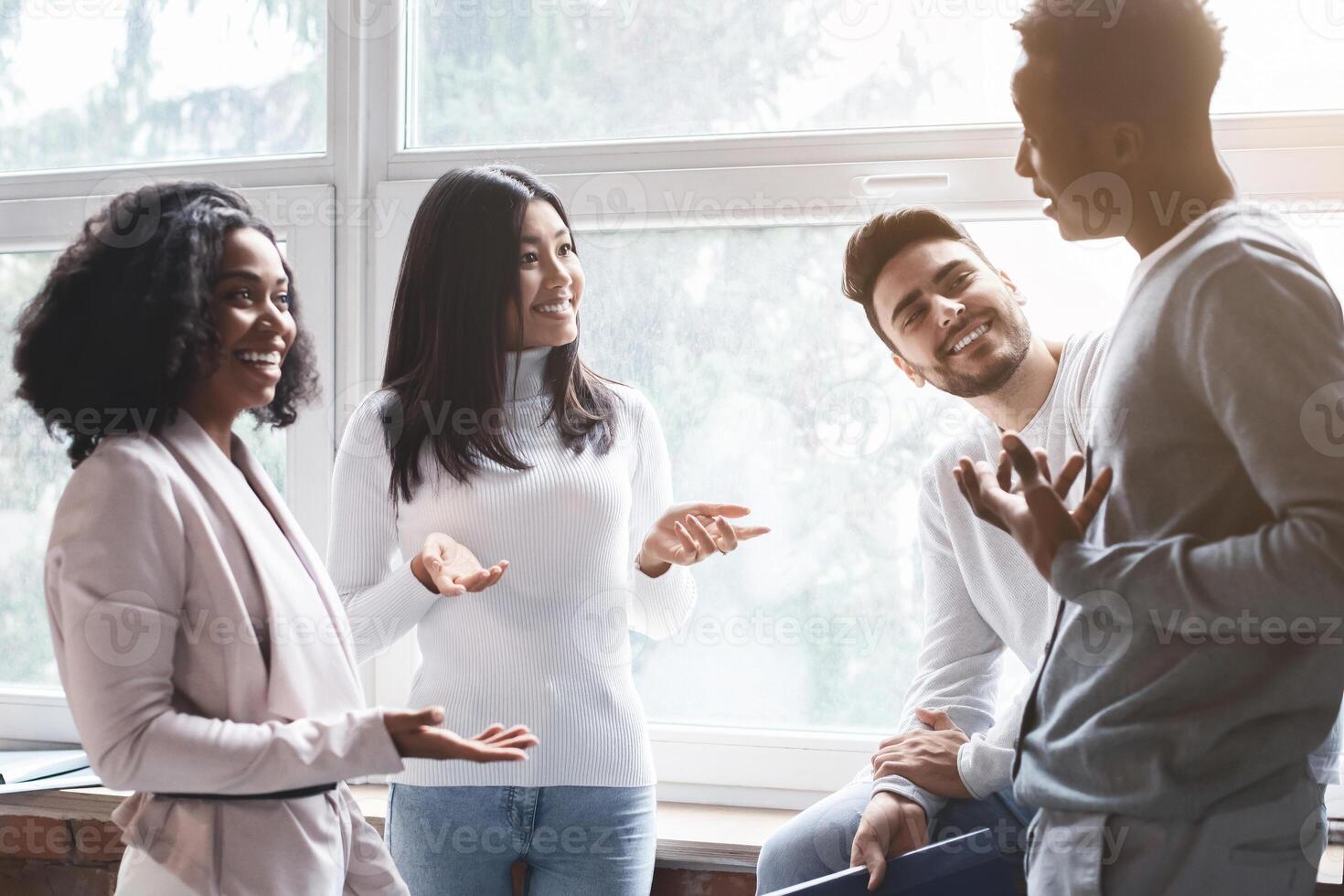 Cheerful multiracial young colleagues having small talk in office, office atmosphere concept photo