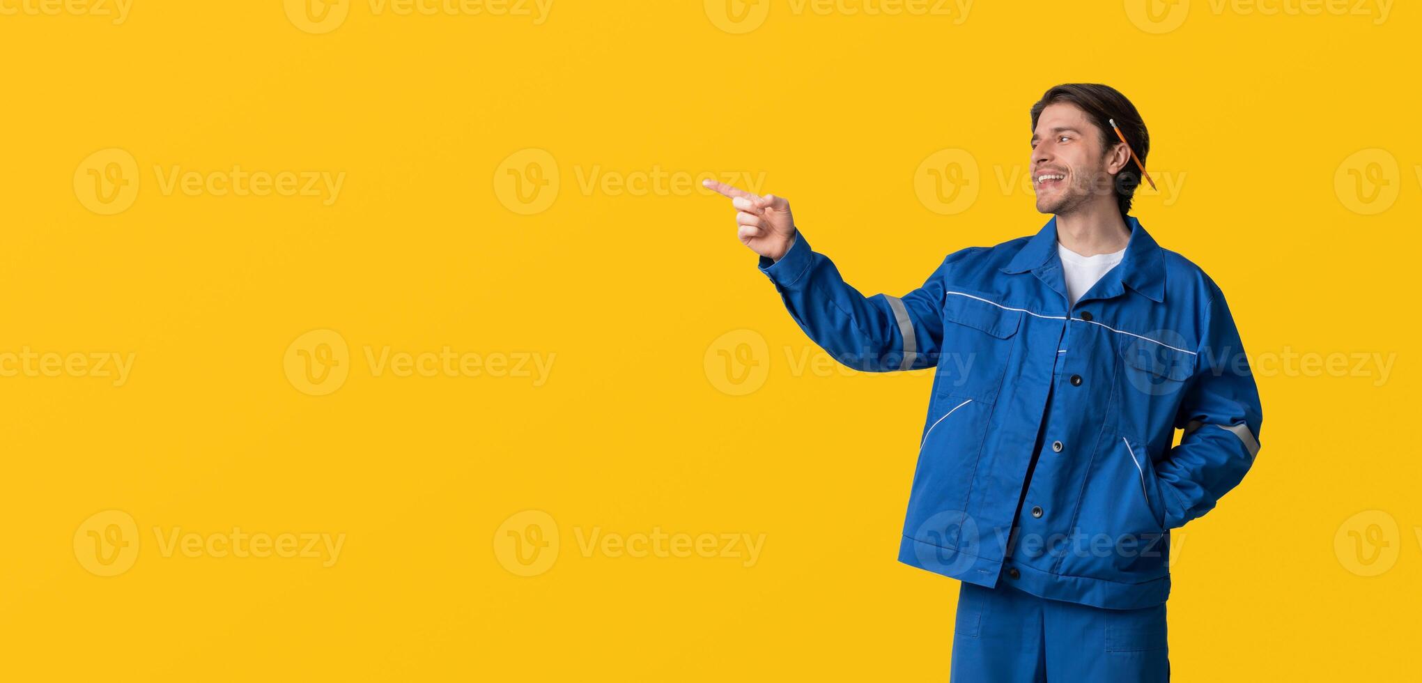 Construction Workers Hire Concept. Portrait Of Young Civil Engineer In Uniform Pointing Aside At Copy Space On Light Background photo
