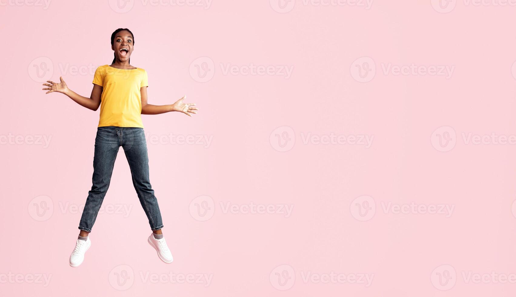 Excited African Millennial Lady Jumping And Shouting In Joy Over Pink Background. Studio Shot, Full Length, Copy Space photo