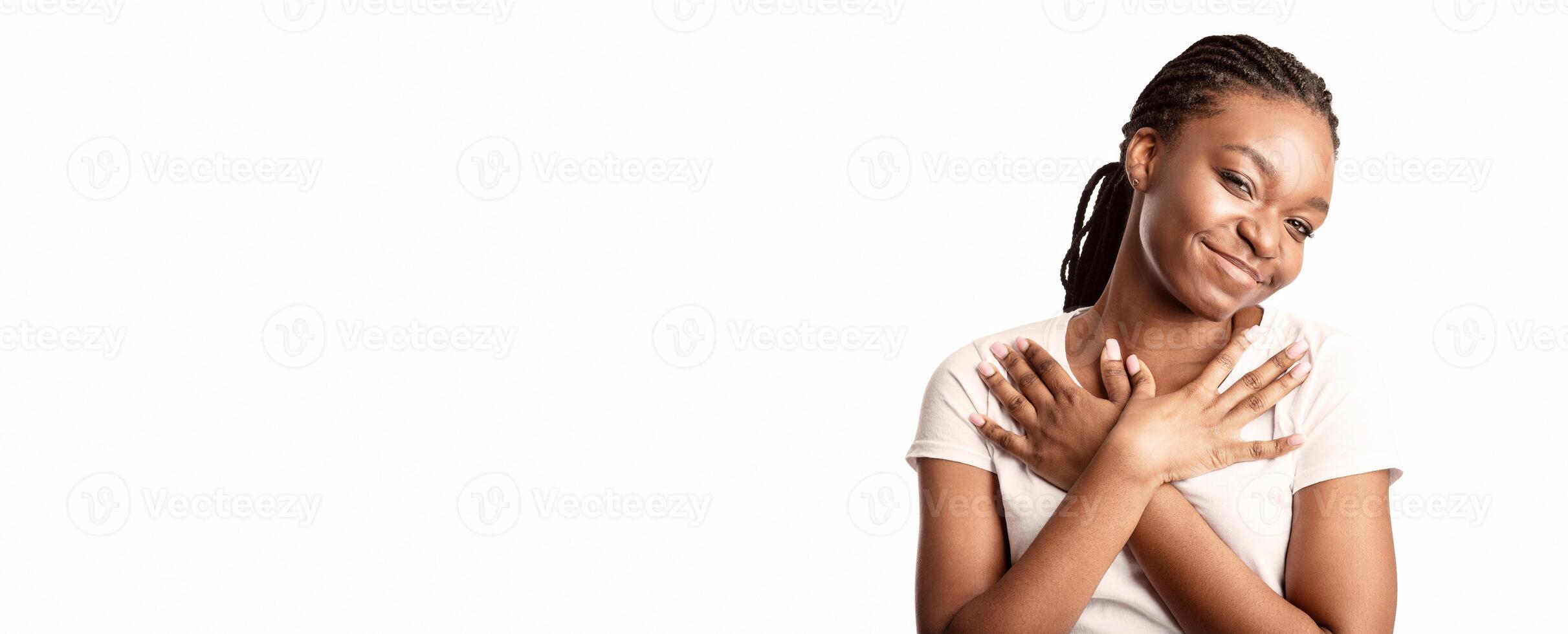 Gratitude. Thankful Black Lady Pressing Hands To Chest Standing On White Background, Smiling To Camera. Studio Shot photo