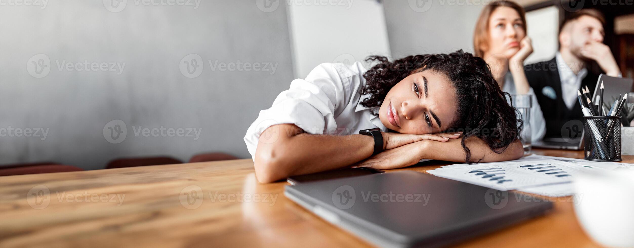 Unhappy Employee. Sad African Businesswoman Sitting Resting Head On Hands During Corporate Business Meeting In Office. photo