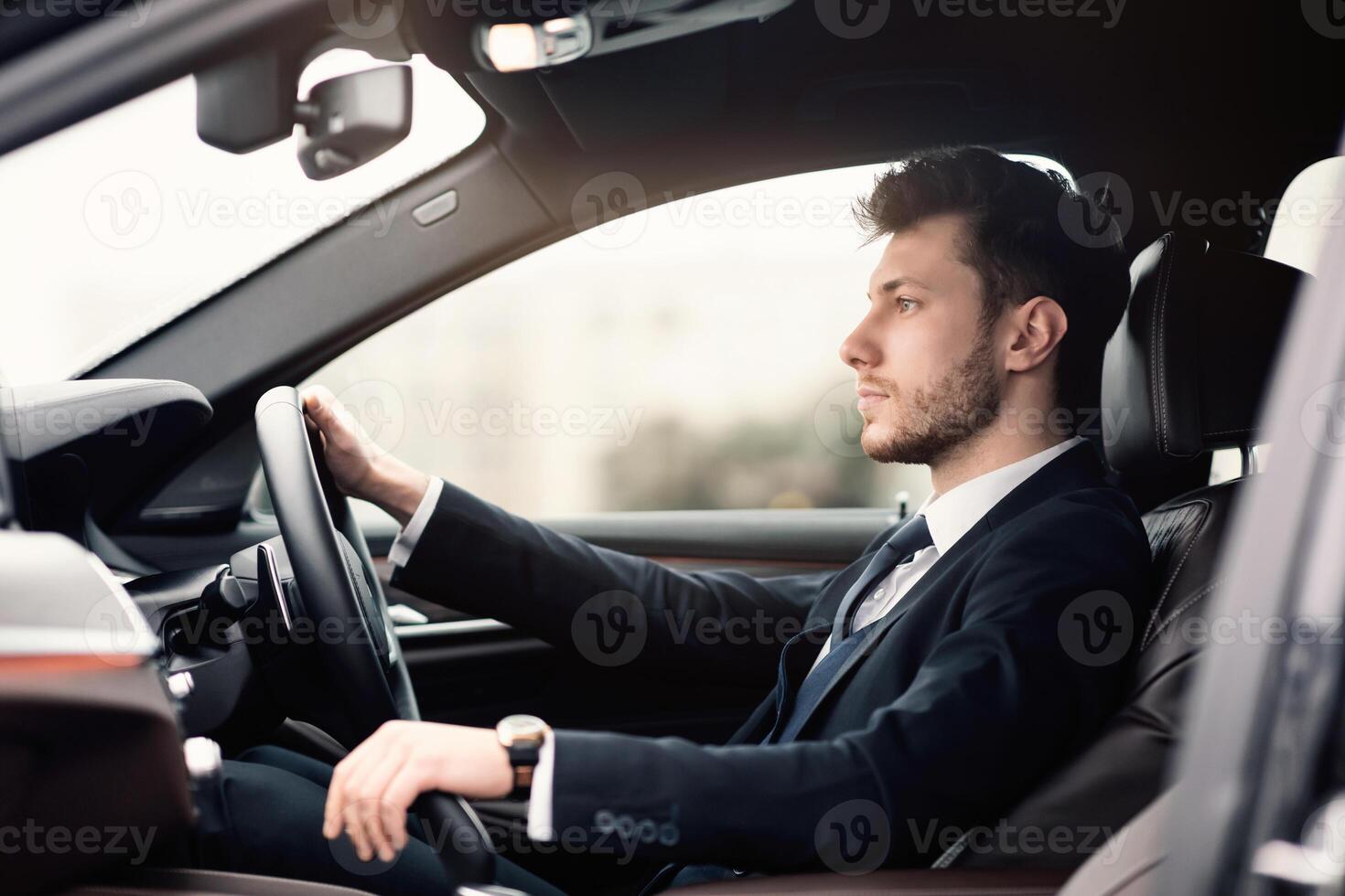 Confident Businessperson. Side view portrait of handsome bearded young professional driving car in the city photo