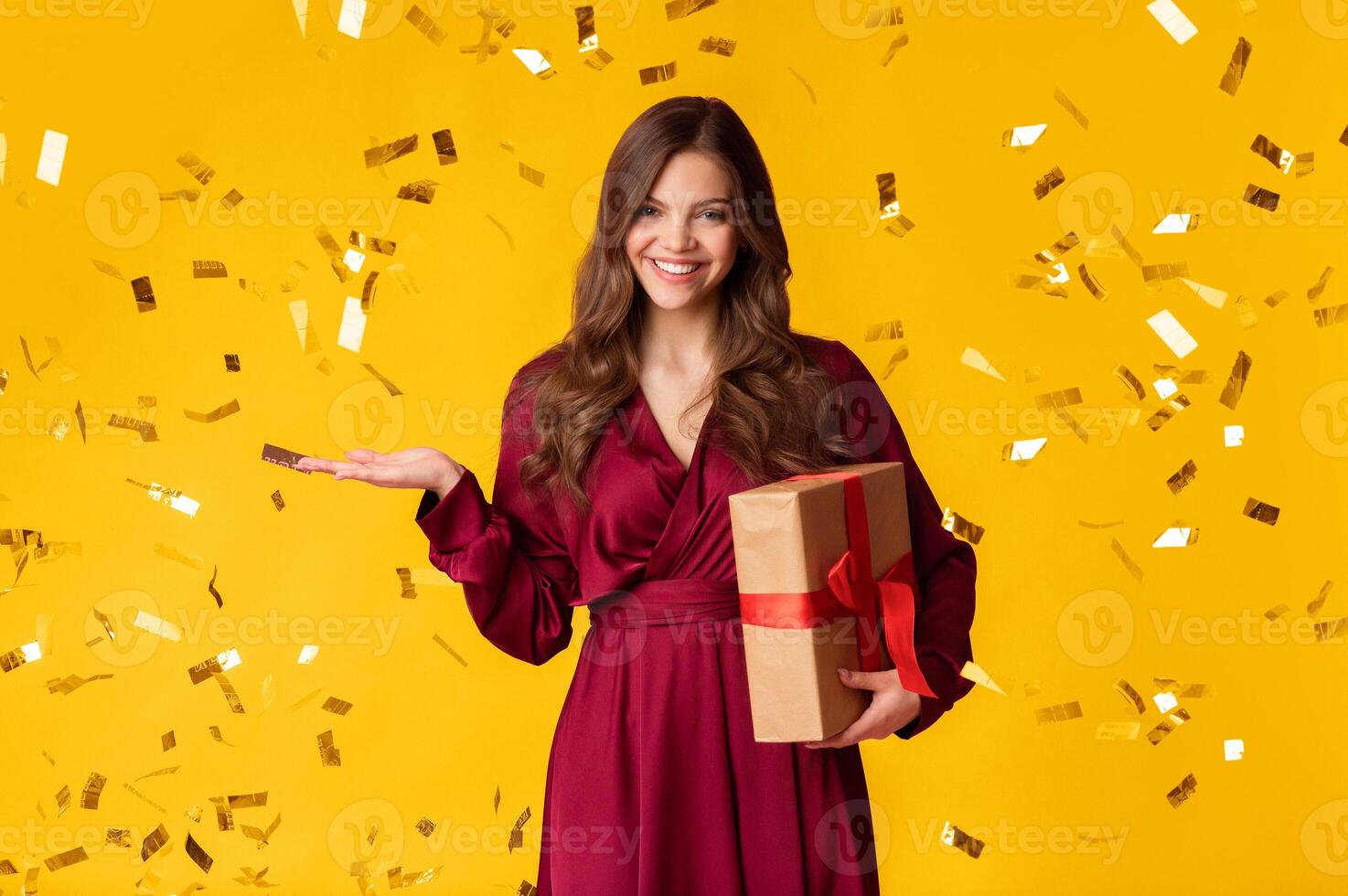 Happy Millennial Lady Holding Gift Box And Posing Over Colorful Background With Falling Confetti photo