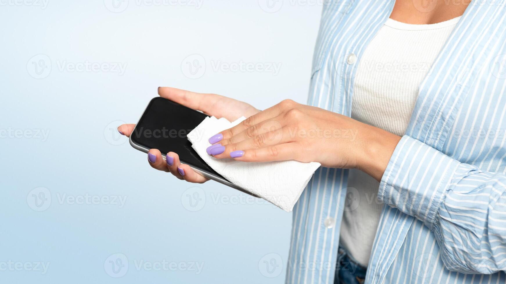 Disinfection Concept. Unrecognizable Woman Disinfecting Smartphone Cleaning It With Sanitizer And Tissue Over White Studio Background During Coronavirus Pandemic. Cropped photo